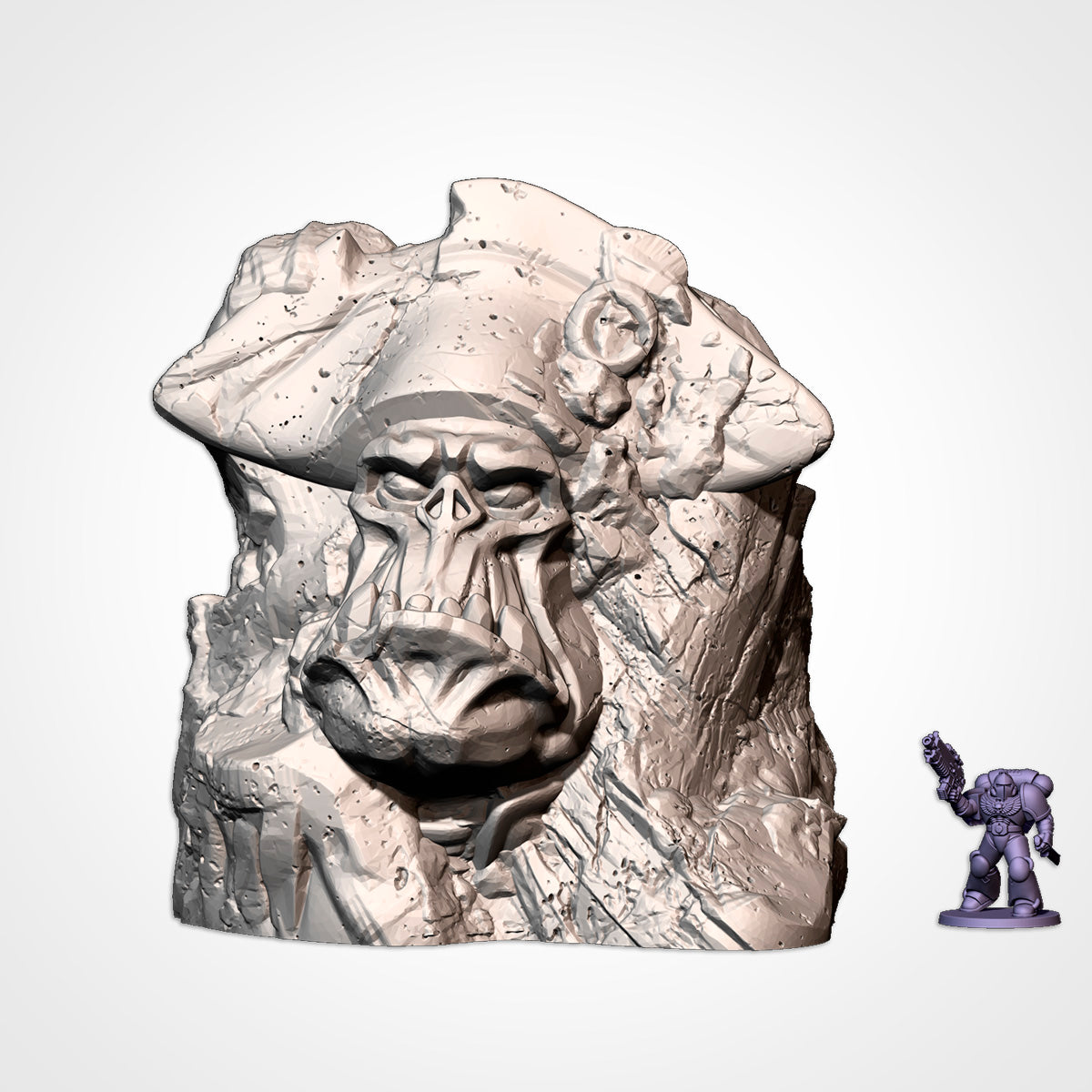 Monument 1: orc head in a bicorne hat set in a rock outcrop, beside a 32mm figure (Txarli Factory render)