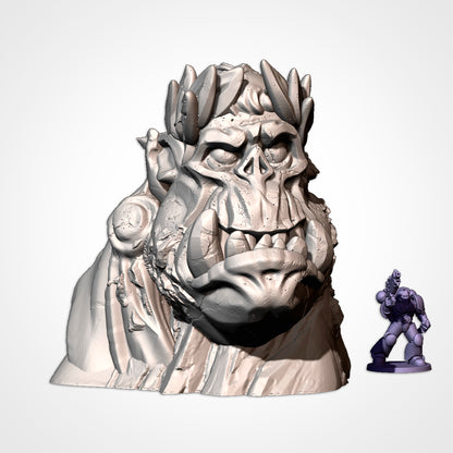 Monument 5: orc head wearing a laurel wreath and cloak, beside a 32mm figure (Txarli Factory render)
