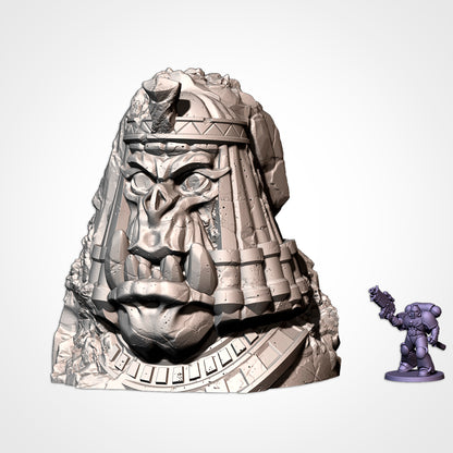 Monument 6: orc head in a pharaoh headdress and collar, beside a 32mm figure (Txarli Factory render)