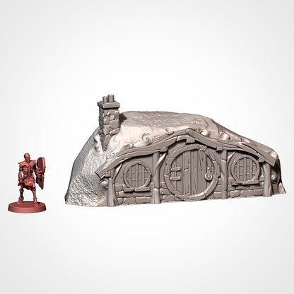 Burrow 6: front view beside a 32mm figure, two round windows and a double-pipe stone chimney (Txarli Factory render).