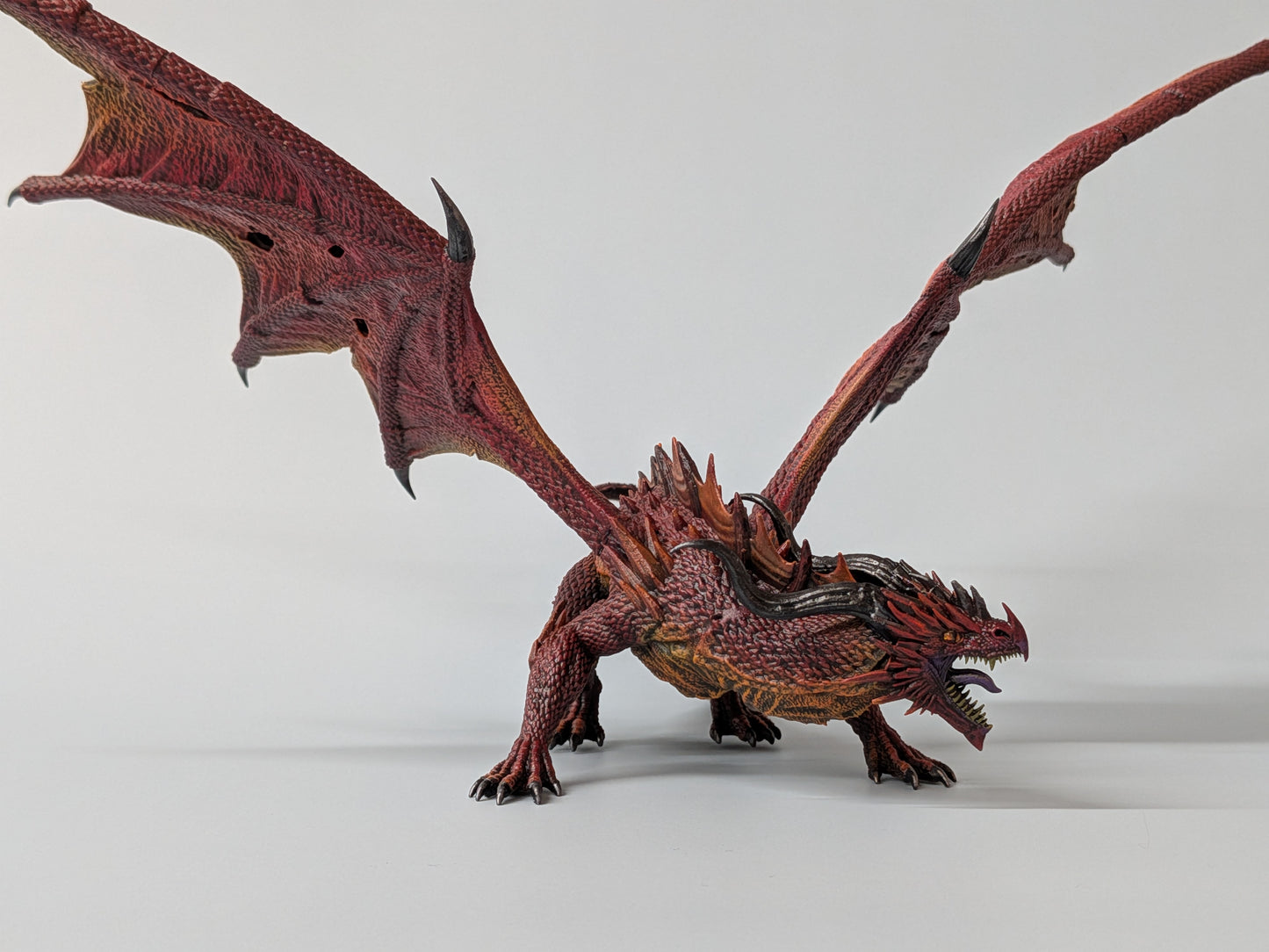 Painted ancient red dragon miniature with battle-torn wings