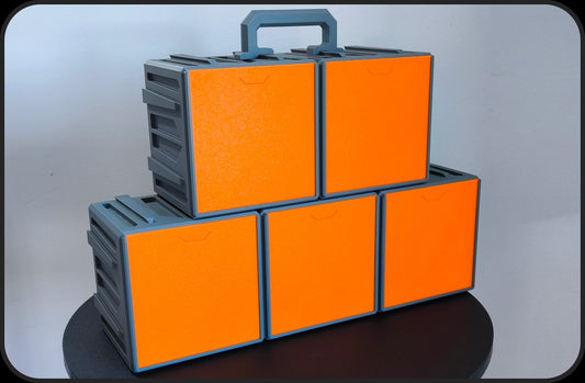 Five printed Cubes To Go cases stacked, orange front covers, grey handle on top (Txarli Factory photo)